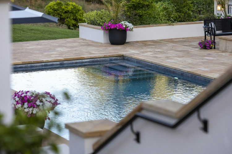 A home swimming pool with a tiled waterline and stone coping
